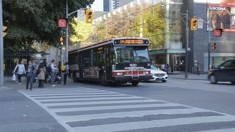 Pan shot of a city bus going by at a busy downtown intersection Video stock 70636422