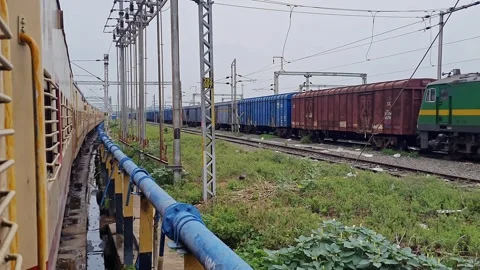 Pan shot of a goods train and a passenger train halted side by side on para.. Stock Footage 313381493