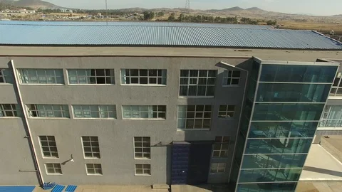 Pan shot of a large building a blue corrugated iron on the roof 스톡 동영상 107193032