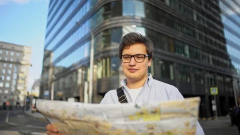 Pan shot of man with map standing in the center of the roading looking at the 動画素材 117427582