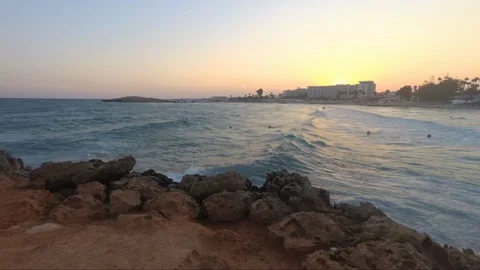 Pan shot of ocean waves. Beach with hotels. Sunset. Video stock 114987310