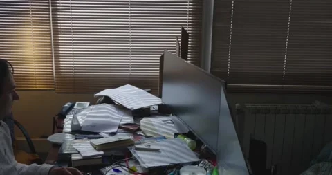 A pan shot of a office with a man working in front of two screens. In the Stock Footage 154282126