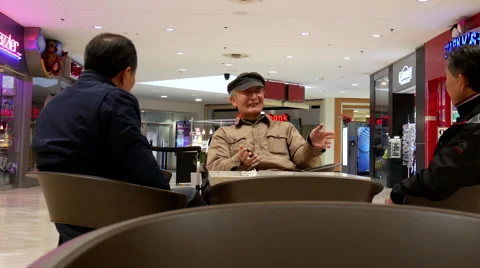Pan shot of old men sitting and chatting at rest area Video stock 68892383