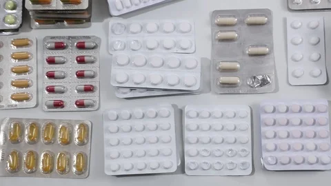 Pan shot over desk full of colorful pills in their blisters Stock Footage 124121772
