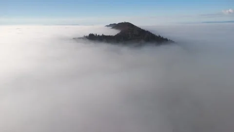 Pan shot over the sea of clouds with a mountain rising above it. Video stock 320934124
