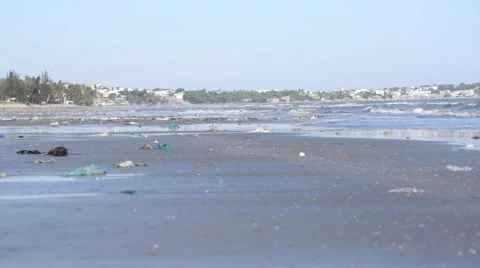 Pan shot of playing children in defocus on beach polluted by trash and garbage Stock Footage 51025219