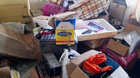 A pan shot reveals a cluttered living room with piles of boxes and furnitur.. 動画素材 307742053