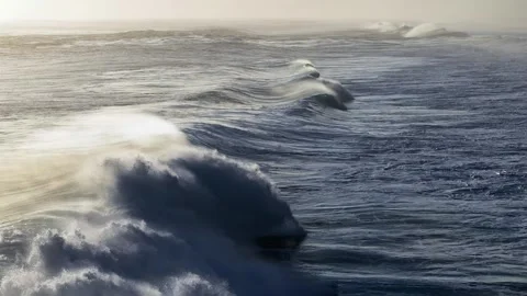 Pan shot of rolling crescent waves crashing Stock Footage 308744197