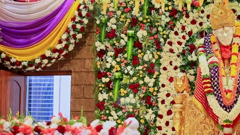 A pan shot of Sai Baba or Sai Ram idol surrounded by floral decorations ins.. Video stock 328011474