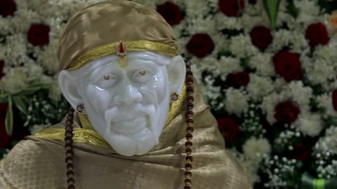 A pan shot of Sai Baba or Sai Ram idol surrounded by floral decorations ins.. 스톡 동영상 328011492