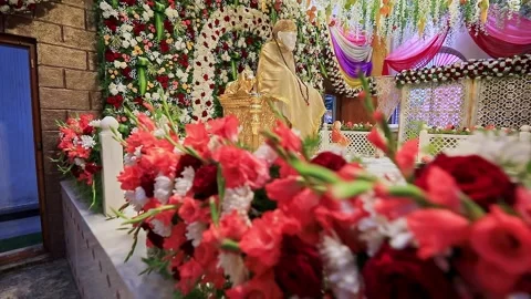 A pan shot of Sai Baba or Sai Ram idol surrounded by floral decorations ins.. 스톡 동영상 328011523