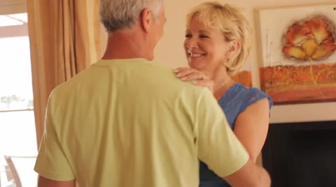 Pan shot of senior couple dancing and falling on sofa and hugging Stock Footage 43622305