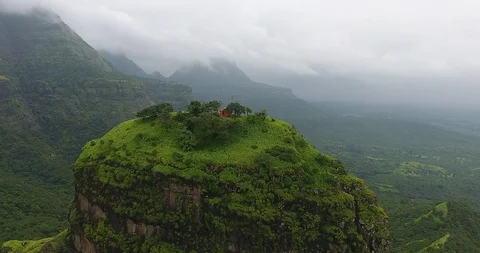 Pan shot of a structure on top of a mountain in a lush green forest Stock Footage 117004713