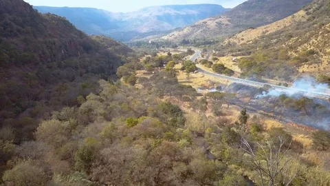 Pan shot through smoke of small controlled bush fire near road and rail  Stock Footage 78584223