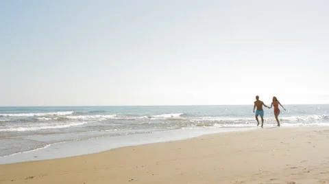 Pan shot of young couple running on beach Stock Footage 43619829