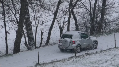 Pan: Silver-gray car (SUV) driving on a snowy farm track in winter, snow, trees Stock Footage 99872491