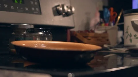 Pan sitting on a stove top with timer blinking in the background. Shallow Stock Footage 101115798