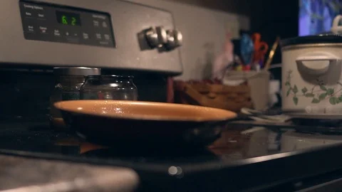 Pan sitting on a stove top with timer blinking in the background. Shallow Stock Footage 101115971
