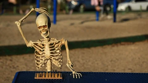 Pan of Skeleton Playing Chess in the Park doing a Confused Head Scratcher Stock Footage 97046008