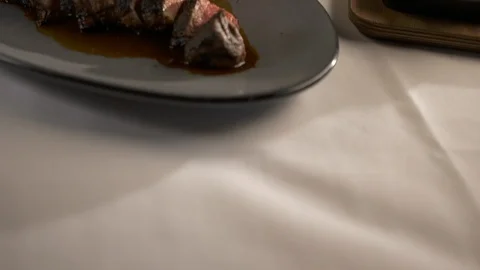 Pan up of sliced tomahawk steak with sides and wine Stock Footage 112576028