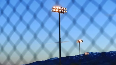 Pan of Softball Field Lights Through Chain Link Fence - Shallow Depth of Fiel Stock Footage 106921254
