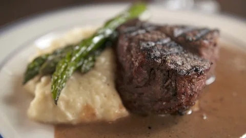 Pan up of steak with sides to wine  Stock Footage 112575944