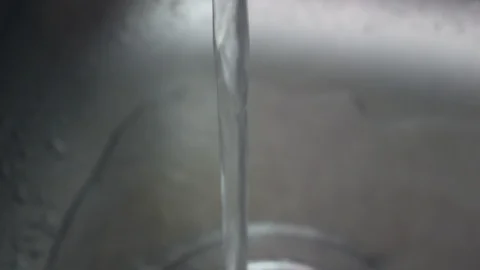 Pan up on stream of water coming from running tap in stainless steel sink Stock Footage 104782479