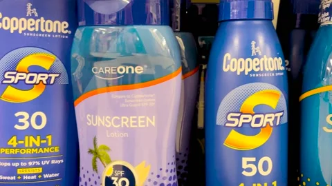 Pan of sun tan lotion on a retail display Coppertone variety Stock Footage 175484398