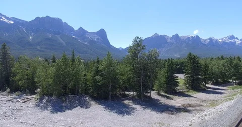 Pan then climb over forest with Canadian Rockies Stock Footage 86296035