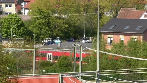 Pan: Train leaving the station. Small village, electricity power plant nearby Video stock 76764789