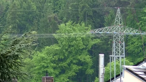 Pan: Trees, a forest, a power pylon, chimneys and a rooftop in the rain Stock Footage 76783856