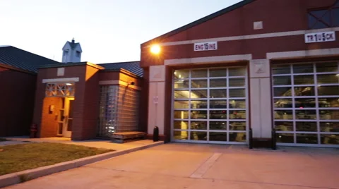 Pan to two firemen talking outside of a fire department Stock Footage 66548749