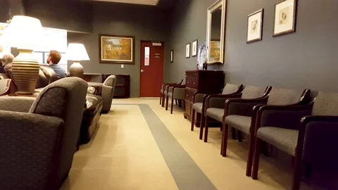 Pan-Unidentified patients wait in plush medical waiting room to be seen Stock Footage 93811142