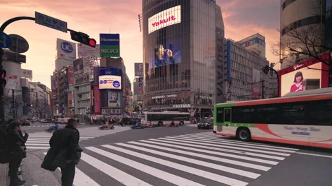 Pan video of crowd waiting and crossing at the Shibuya Intersection at sunset Video stock 127629360
