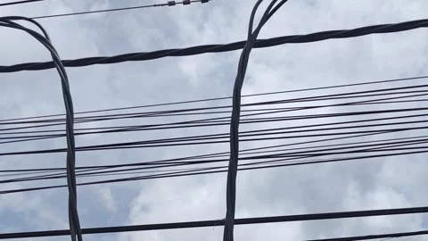 Pan up video of cut twisted aerial cables hanging against a cloudy sky. Stock Footage 345203802