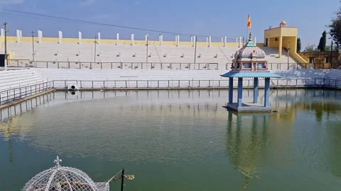 A pan video of a small temple amidst a Pushkarani or Kalyani pond with an i.. Stock Footage 308285501