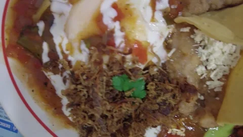 Pan view of a mexican breakfast with egg, beans, hot sauce, suckling pig 動画素材 245588935