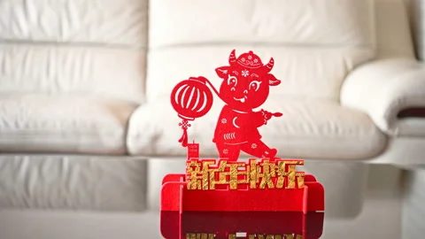 Pan view ox mascot with a lantern in front of a sofa as symbol of Chinese New Stock Footage 147843892