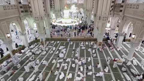 Pan up view of pilgrims in 'ihram' clothes rest inside Al Haram Mosque in Makkah Stock Footage 274472635