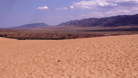 Pan of the view from the sand dune in the desert to the mountains on the horizon Stock Footage 143052003