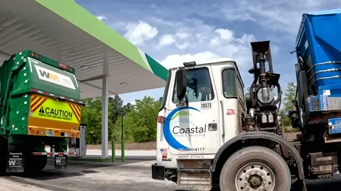 Pan of Waste management trash trucks in line at a Natural Gas and pumps retai Stock-Footage 180134023
