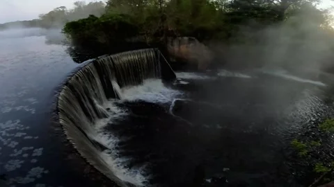 Pan of a water fall lake runoff fog and steam over the water early morning go Stock Footage 179211612