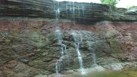 Pan up of waterfall trickling off of river Stock Footage 80271154