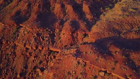 Pan up while flying over rocky terrain at sunrise in Monument Valley Stock Footage 89022147