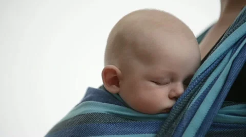 Pan from white background to Close Up of sleeping Baby in baby sling Stock Footage 21781318