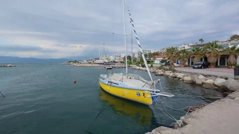 Pan wide angle of yellow sailing boat anchored near coast in Greek marina Stock Footage 337458245