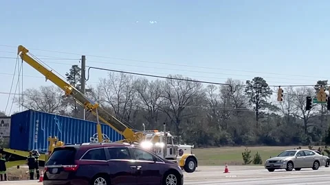 Pan in to a wrecker crew picking up a tracker trailer that overturned when ma Stock Footage 149281307