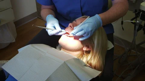 Pan from Xray to Patient Getting Teeth Cleaned by Dentist Video stock 43309034