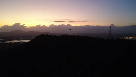Panama flag flying high over silhouette of hills at sunset with city lights  Stock Footage 327103117