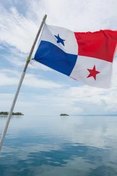 Panamanian Flag waving on a pvc wooden pole with blue sea in background Stock Photos